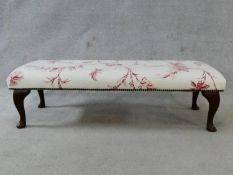 A floral upholstered footstool on cabriole supports. H.33xL.115xW.46cm