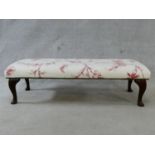 A floral upholstered footstool on cabriole supports. H.33xL.115xW.46cm