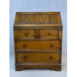 A mid century oak country antique style bureau with linen fold carving to the fall with fitted