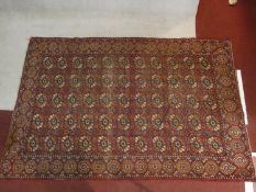 A Bokhara carpet with all over repeating gul motifs on a madder ground contained within stylised