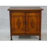 An early 20th century country oak style side cabinet with carved panel doors on squat square