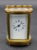 A miniature French brass five glass oval carriage clock with bevelled glass plates, white enamel