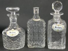 Three cut crystal drinks decanters, two with stoppers and one with a silver plated top, each with