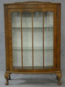 A mid century figured walnut Art Deco style display cabinet with a glazed door enclosing shelves
