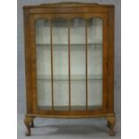 A mid century figured walnut Art Deco style display cabinet with a glazed door enclosing shelves