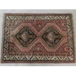 An Eastern rug with double stepped lozenge medallions on a blush ground within stylised floral