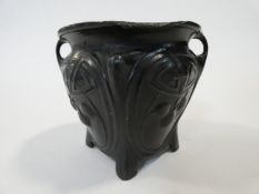 An Art Nouveau twin handled patinated pewter vase with stylised foliate and cherry design, on four