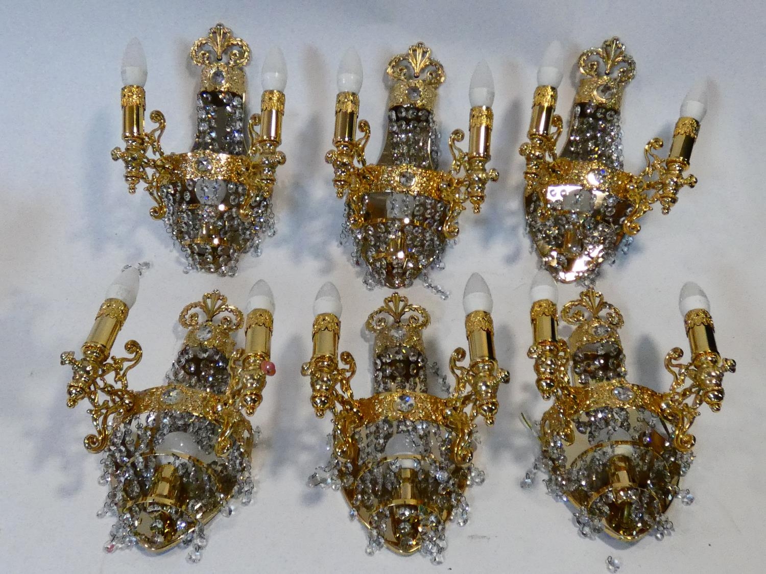 A set of six gilt metal twin branch wall candelabras with crystal drops. H.38cm