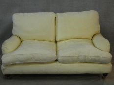 A Multiyork Howard style two seater sofa in jacquard upholstery on turned tapering supports on brass