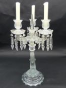 A glass three branch table candelabra with crystal drops on dolphin support. H.50cm