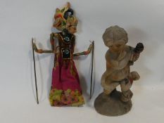 A painted Indonesian stick puppet and a carving of a child seated on a tree stump. H.51cm