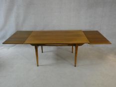 A mid century vintage teak extending dining table with unusual patent rise and fall winding