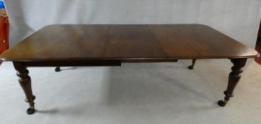 A Victorian mahogany extending dining table with three extra leaves raised on turned tapering