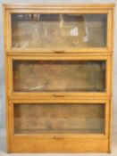 A vintage light oak three section Globe Wernicke style bookcase with patent label for the Meovoto