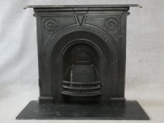 An ornately cast 19th century iron fire surround, mantel shelf and insert with grate on marble