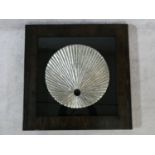 A contemporary carved wood textured silver disk, mounted on black, shadow box framed. H.80 W.80cm