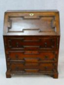 A mid century Jacobean style oak bureau with lozenge inset panels and fall front revealing fitted