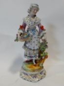 A Meissen style porcelain hand painted figure of a flower girl with her basket and bunch of flowers,