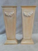 A pair of 19th century style terracotta pedestals decorated with swags standing on stepped plinth