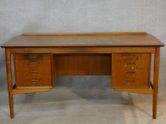 A 1960's vintage Danish teak desk fitted with two banks of drawers opposing open shelves and