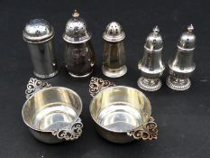 A collection of silver salts and salt and pepper shakers. One pair shaped like quaiches with pierced