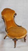 A Victorian mahogany framed nursing chair in gold upholstery on carved cabriole supports. H.90cm