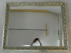 A bevelled glass wall mirror in silvered Art Nouveau style flowing floral design frame. H.135 W.