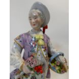 A hand painted porcelain Meissen style figure of a dandy with basket of flowers and holding a
