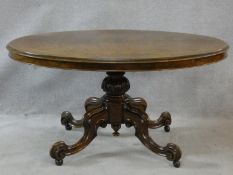 A Victorian burr walnut tilt top dining table on quatreform carved swept supports. H.72 L.137 W.