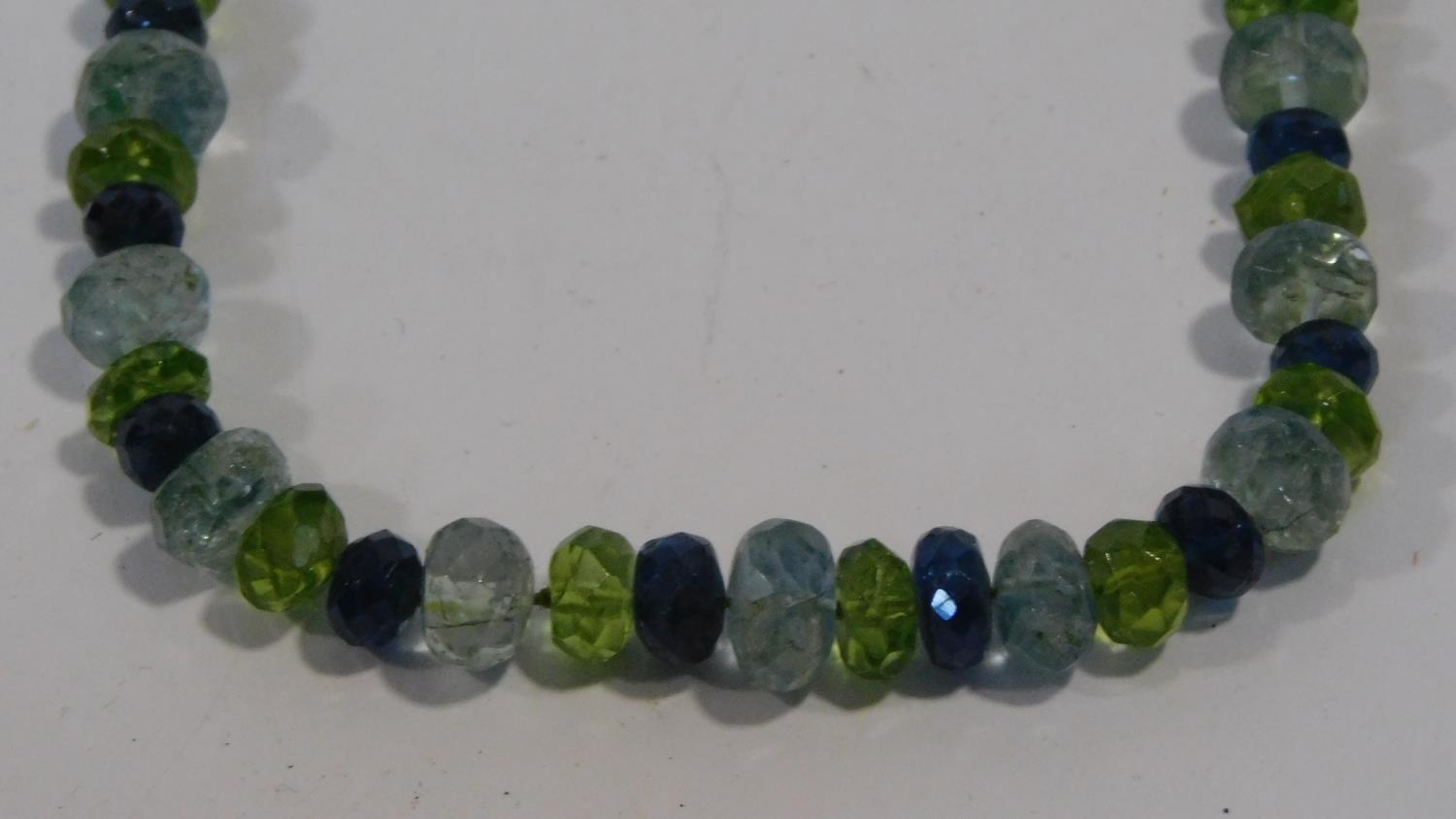 A bespoke faceted Apatite, Aquamarine and Peridot bead necklace with a silk chord loop clasp. L.42cm