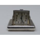 An Art Deco Dunhill silver miniature travel clock, the engine turned case with hinged divided