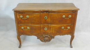 A Louis XV French provincial two drawer walnut commode of arc en arbalete outline with Rococo carved