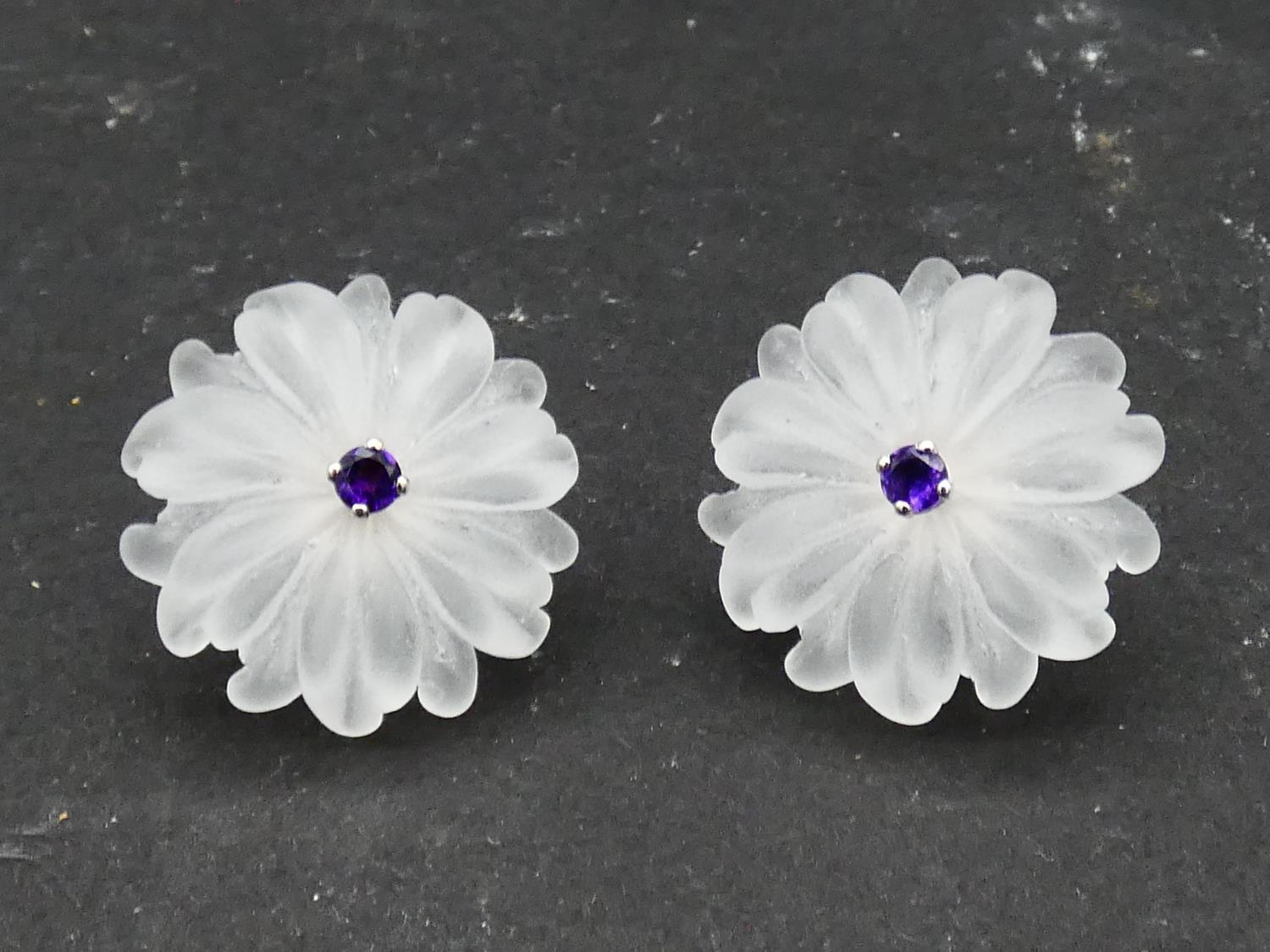 A pair of carved rock crystal daisy earrings each set to centre with a round brilliant cut