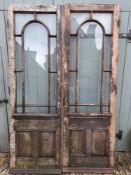 A pair of large oak doors with arched glazed upper sections above panelled lower sections. H.190xW.