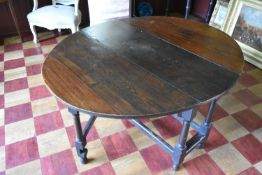 An antique oak drop flap dining table fitted with end drawer on turned and stretchered gateleg