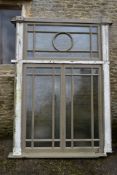 A large painted hardwood window frame of twenty nine double glazed panels with stained glass