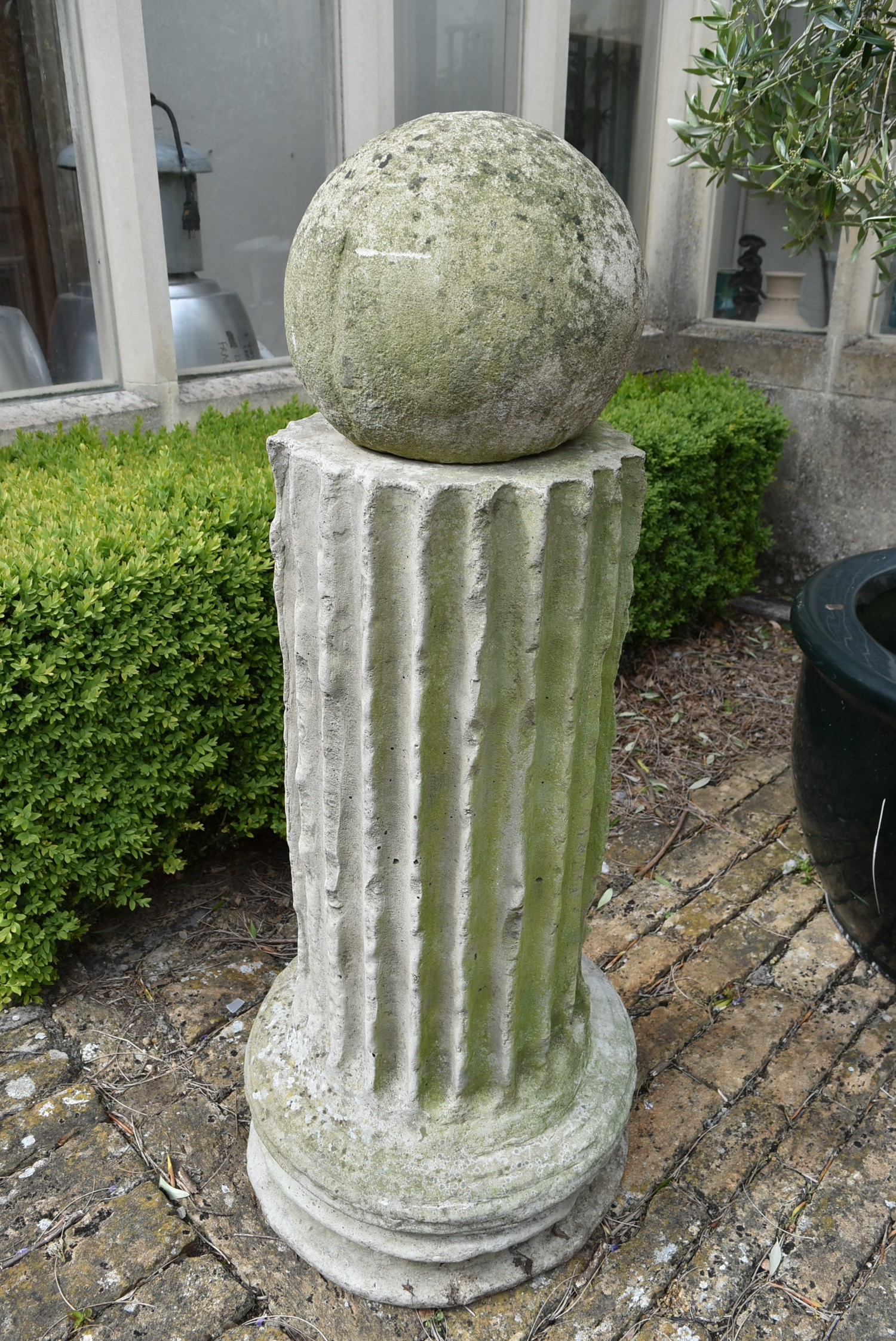 A moulded concrete classical column style plinth with weathered spherical finial. H.128cm