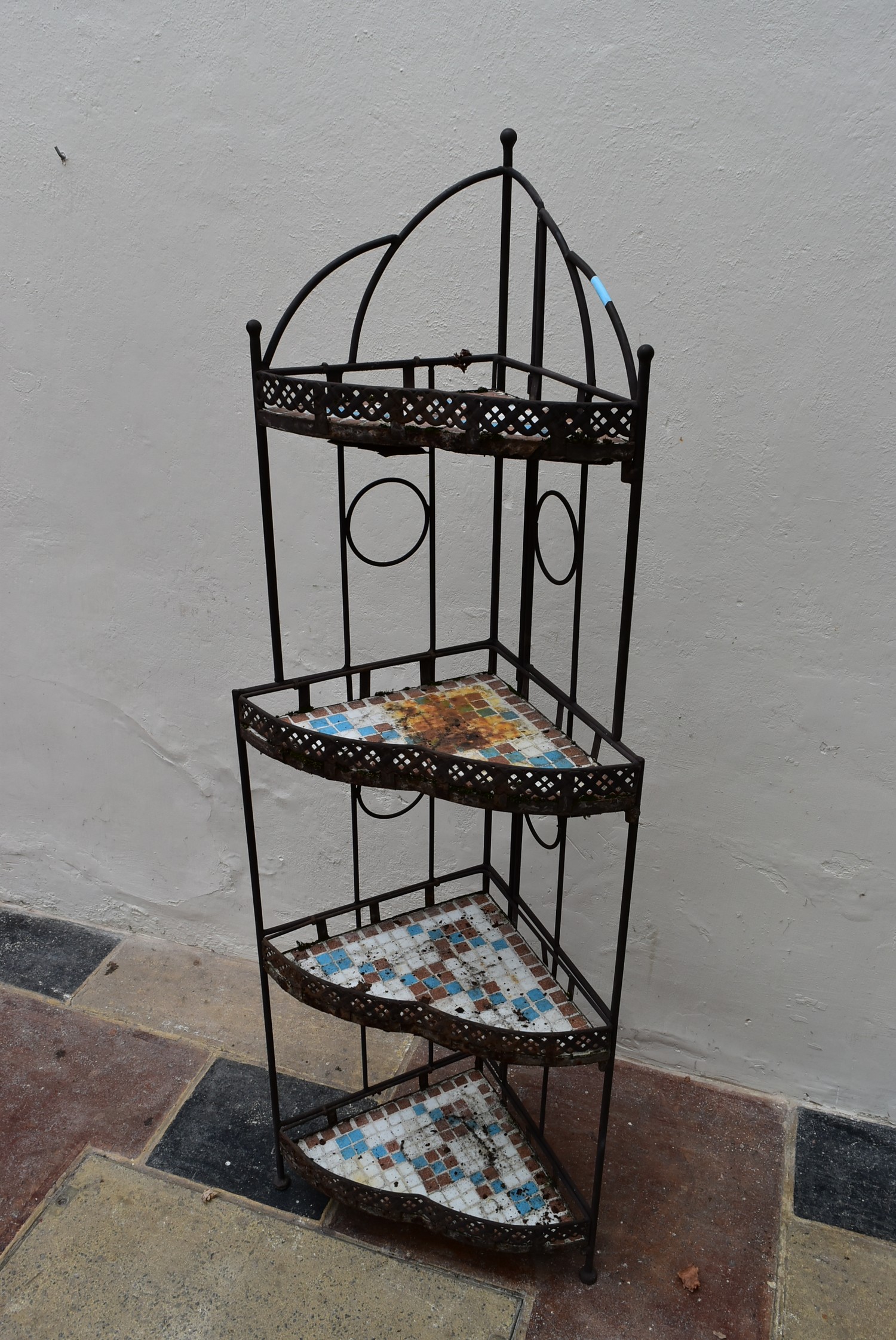 A wrought metal framed four tier corner whatnot with inlaid mosaic tiled shelves. H.138 x W.30cm