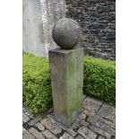 A carved stone garden plinth with weathered spherical finial. H.140cm