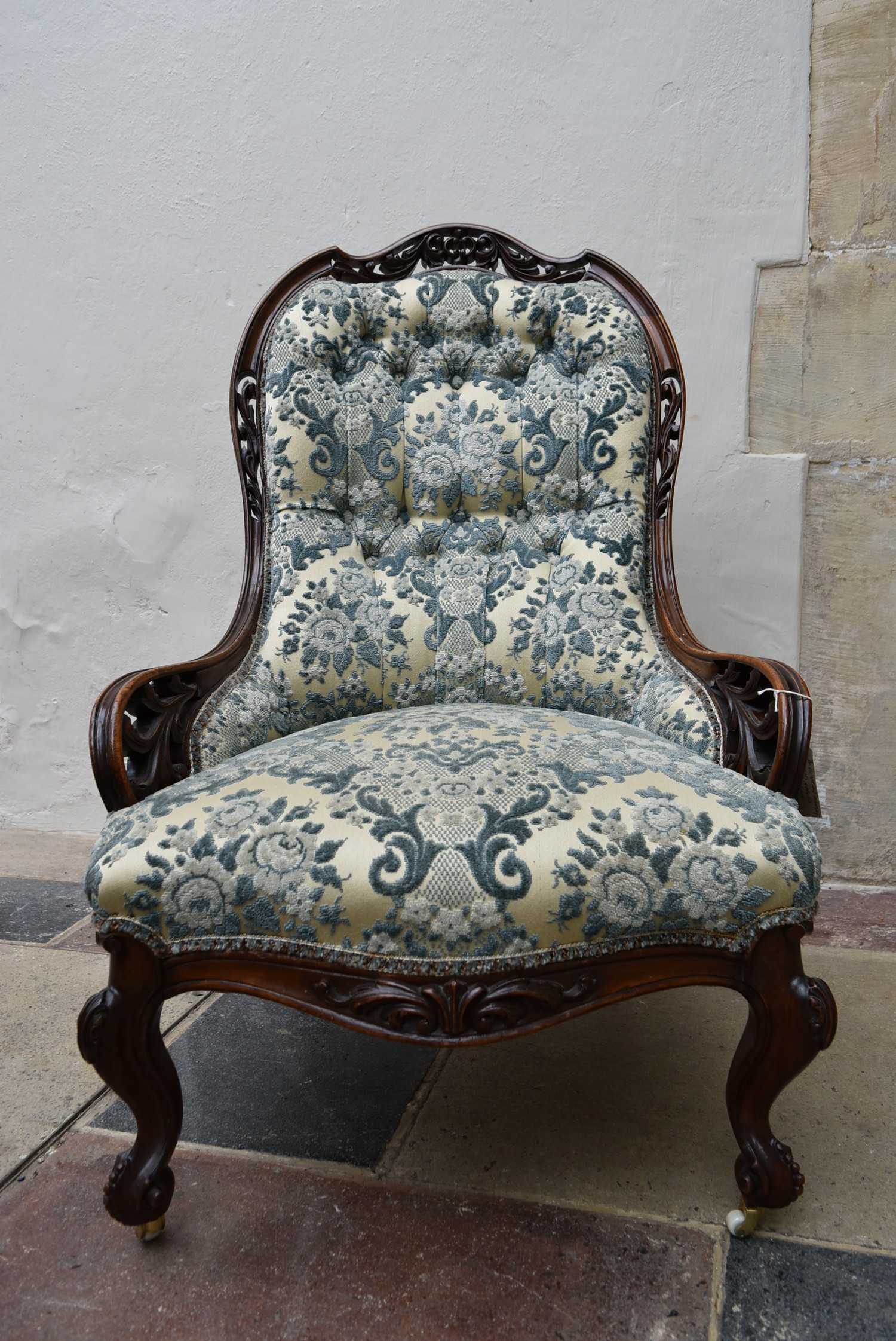 A Victorian mahogany nursing chair with carved and pierced back rail on cabriole supports in deep