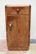 An Art Deco figured walnut pot cupboard with frieze drawer above panel door on plinth base. H.