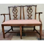A late 19th century mahogany double chair back settee in the Chippendale style with drop in seat