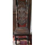 A 19th century Carolean style oak hall chair with carved arched high back above panel seat on turned