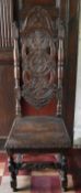 A 19th century Carolean style oak hall chair with carved arched high back above panel seat on turned