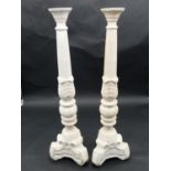 A pair of white painted and carved ecclesiastical candlesticks. H.60cm