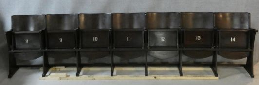 A row of seven vintage theatre seats with laminated plywood backs and seats and painted seat