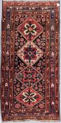 An antique Kazak rug with repeating central medallions and flowerhead and animal motifs contained