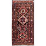 An antique Kazak rug with repeating central medallions and flowerhead and animal motifs contained