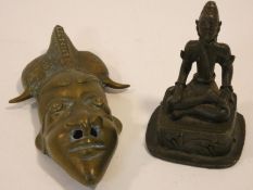 An antique oriental brass mask and seated bronze figure of a deity in lotus position. H.15cm (