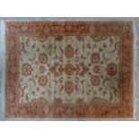 A Ziegler style rug with repeating scrolling floral design across a fawn field within floral